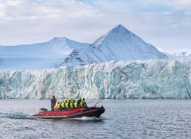 Boat driving on the fjord. Glacier and mountains in the background.
