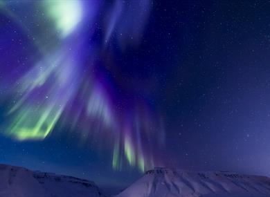 Blue and purple northern lights above the mountains