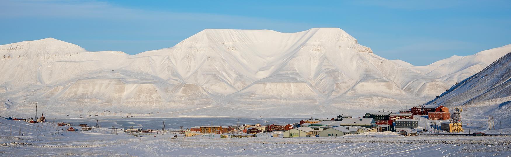 Et bylandskap i sollys med fjell i bakgrunnen