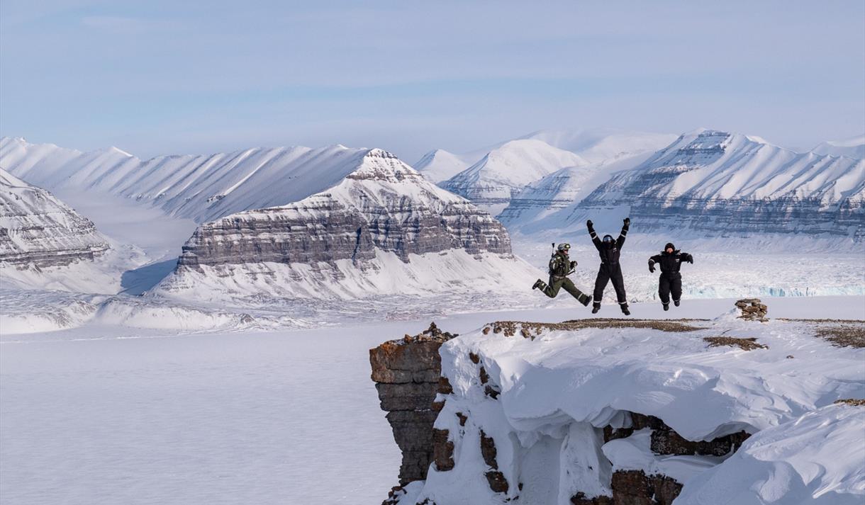People standing on a snowy mountain edge in the Arctic.