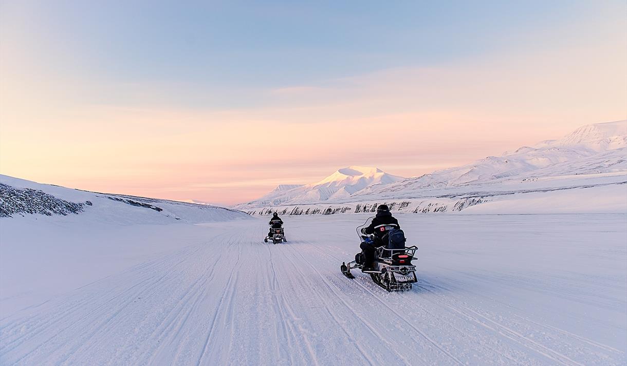 People driving snowmobiles