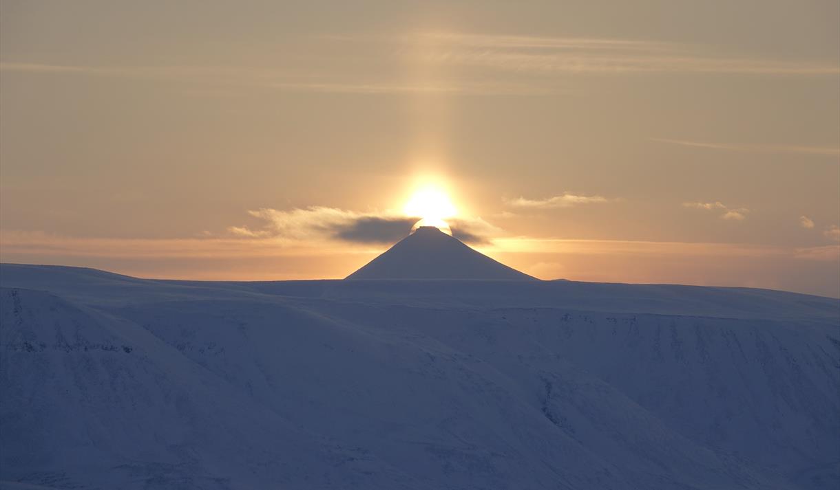 Midnattssola som skinner bak en fjelltopp