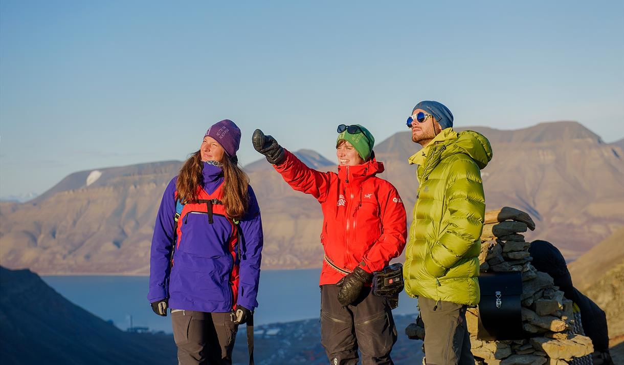 Tre personer på toppen av et fjell