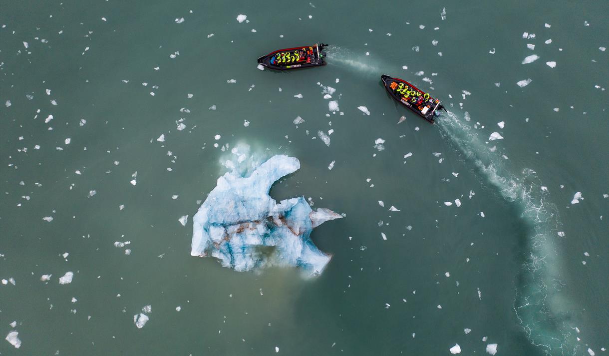 To RIB båter som seiler rundt et isfjell