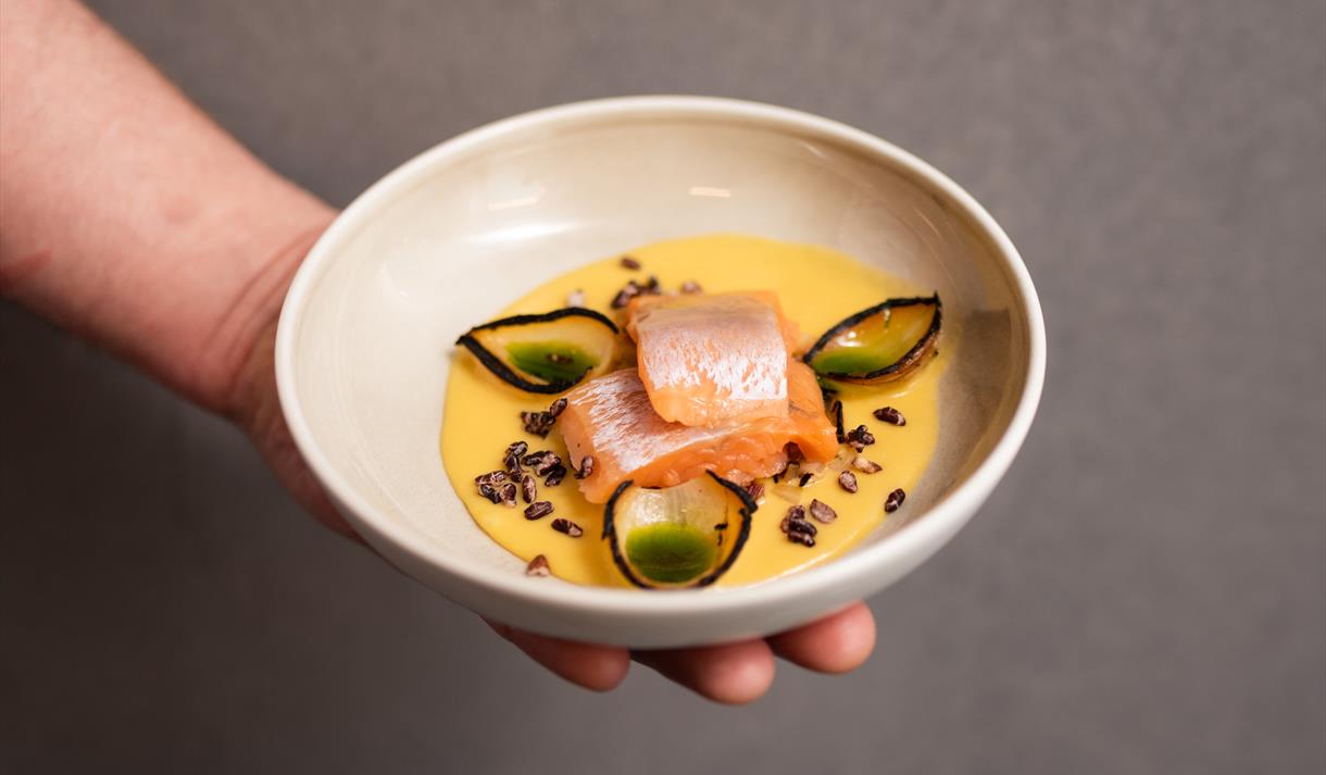 A hand holding a bowl with food inside