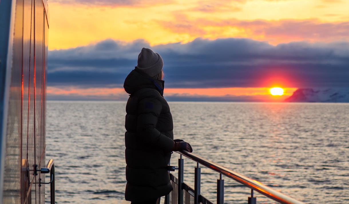 Person som ser på solnedgang fra en båt