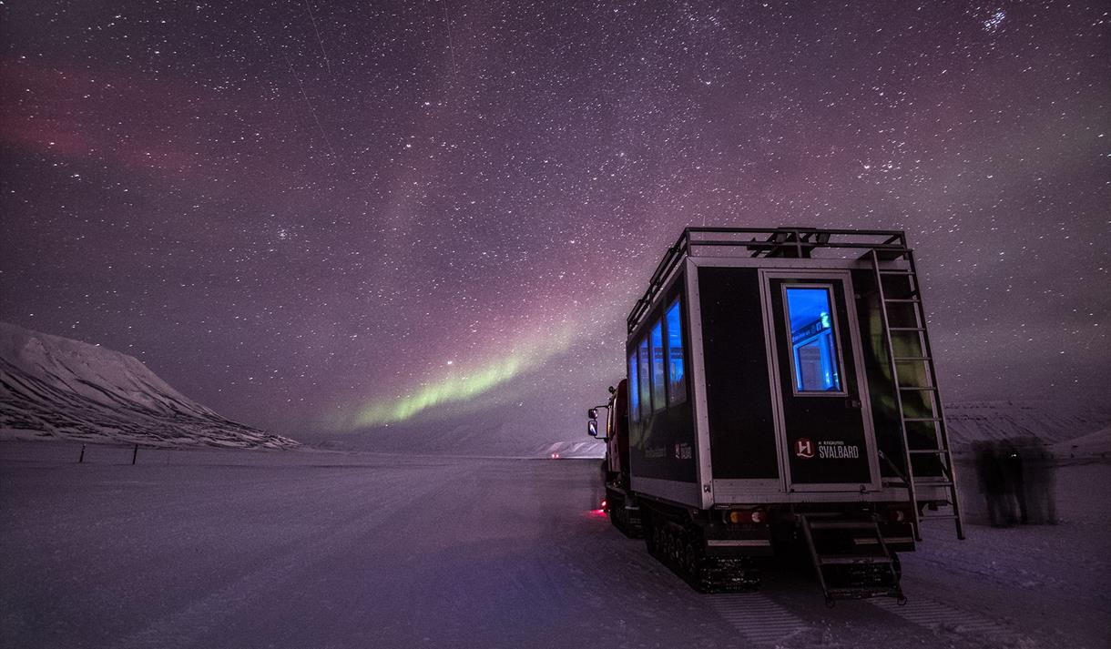 Northern Lights shining in the skies above a snowcat