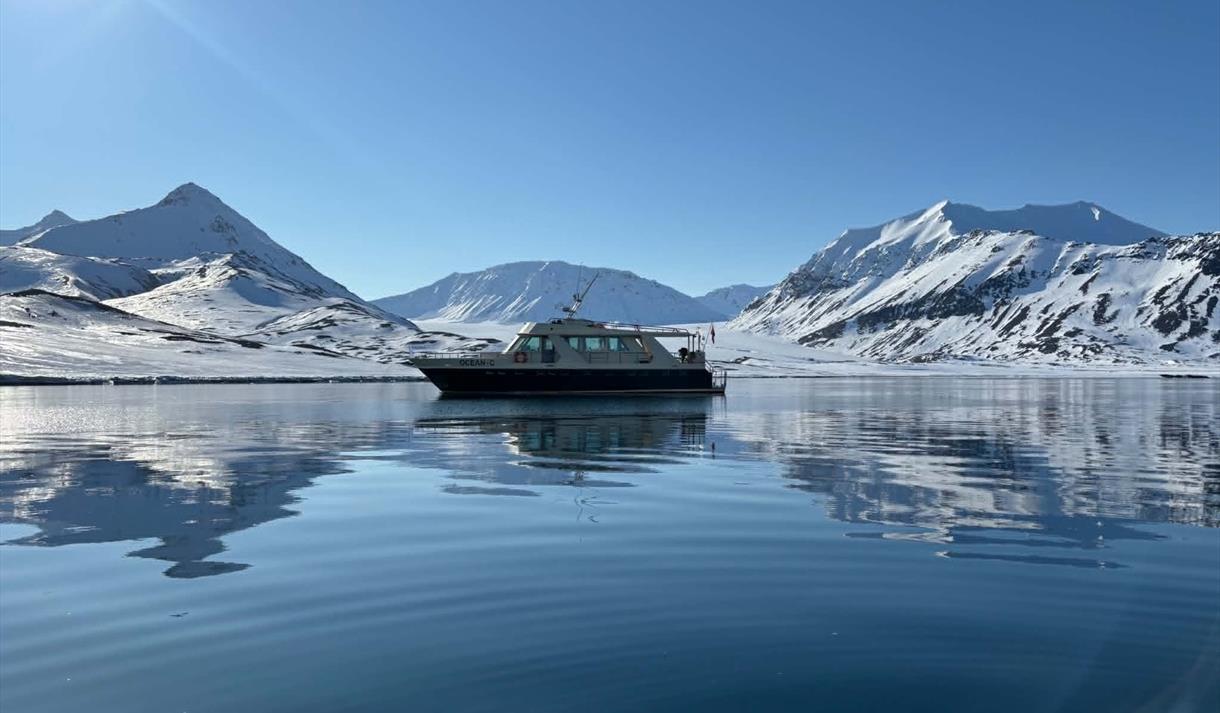 Båt ligger i havet foran et Arktisk landskap