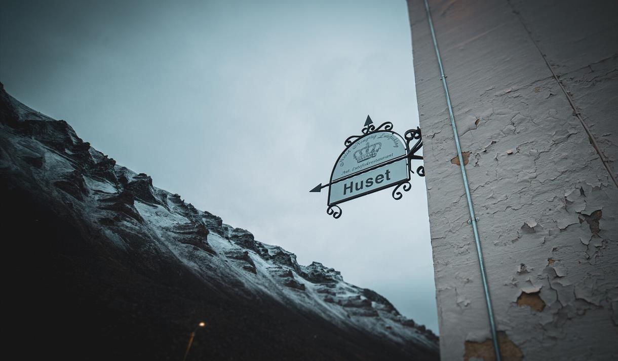 Historisk skilt med snødekte fjell i bakgrunnen.