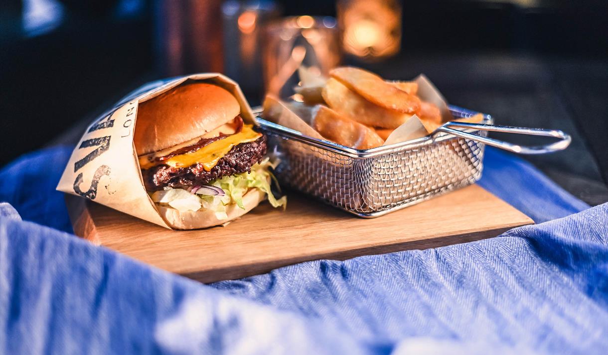 A burger and chips on a wooden serving plate