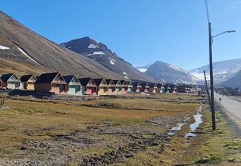 Fargerike hus i Longyearbyen med fjell i bakgrunnen