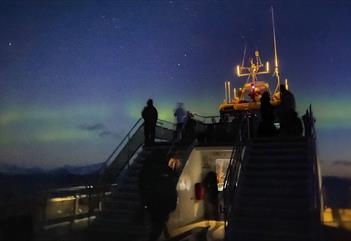 People on a boat watching northern lights