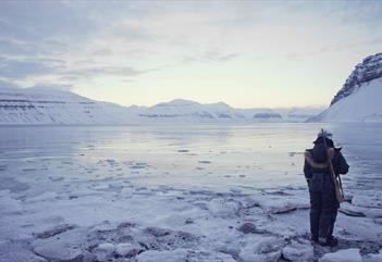 Guide standing by the ice with a rifle