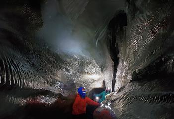 Guests exploring an ice cave with hedlamps on