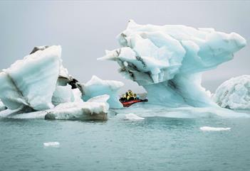 A boat in between pieces of ice floating at sea