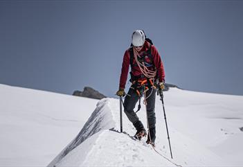 A person with glacier safety equipment hiking on a glacier