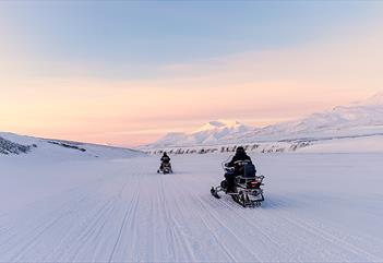 People driving snowmobiles