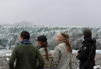 Fire personer som ser ut mot isbreen i bakgrunnen.