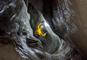 A person climbing inside an ice cave