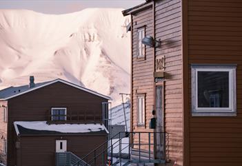 Gjestehuset i forgrunnen med et fjell og en annen bygning i bakgrunnen