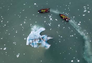To RIB båter som seiler rundt et isfjell