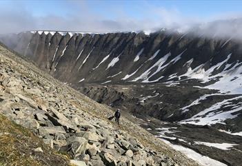 A person on the way up the side of Sarkofagen by foot together with a dog