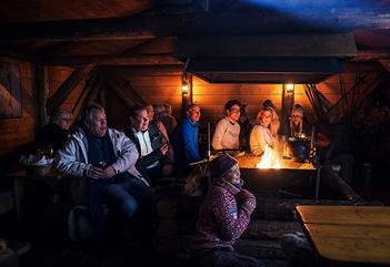 Gjester som følger med på et foredrag inne i hytta på Camp Barentz