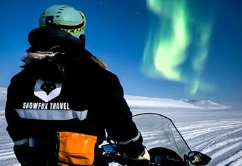 Northern lights under a frozen waterfall - by snowmobile - Snowfox Travel