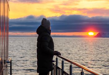 Person on board a boat, looking at the sunset