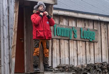 A person standing on some stairs in front of Tommy's Lodge