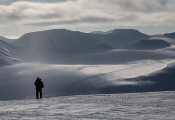 En person som står for seg selv og ser utover et snødekt landskap