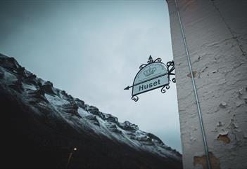 Historisk skilt med snødekte fjell i bakgrunnen.