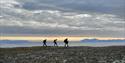 Three persons hiking along the shore