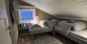 Et soverom på Nordenskiöld Lodge med to oppredde senger og et vindu med tundralandskap i bakgrunnen