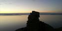 The cairn on top of Fuglefjella in sillhouette against the fjord Isfjorden in dusk light conditions