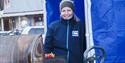 An employee from Coop Svalbard standing in a blue tent while grilling food