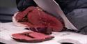 Meat being sliced with a knife on a cutting board