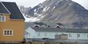 Buildings in Ny-Ålesund in the foreground, with a tall mountain in the background with small spots of snow