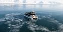 A boat (MS Bard) sailing through thin drift ice on a fjord with mountains in the background