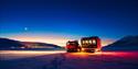 A snowcat with lights on the horizon in the background