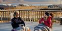 Two guests sitting outdoors with blankets drinking coffee on a balcony