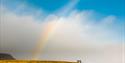 A group of people standing under the rainbow
