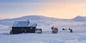 People on snowmobiles outside Juva Cabin