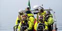 Several people in open RIB observing something in the fjord.