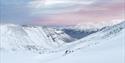 Viewpoint from the snowcovered glacier down towards town. mountains and a pink sky is visible in the background