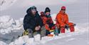 Three persons sitting in the snow