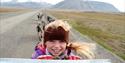 A kid sitting on the dogwagon, smiling and enjoying the trip