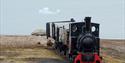 An old locomotive on rails in Ny-Ålesund with a fjord in the background