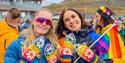 Two persons with mittens and flags in the pride colours