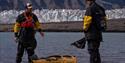 A guide instructing a guest on kayaking while gesturing towards a kayak on the ground